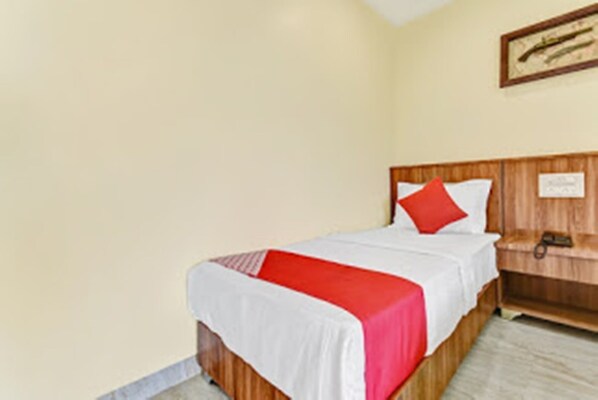 Una habitación de hotel con una cama, una mesita de noche y un reloj de pared.