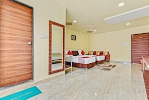 A hotel room with a wooden door, a large mirror, a bed with red and white bedding, and a small desk. - Hotel Manik (Chhatrapati Sambhajinagar)