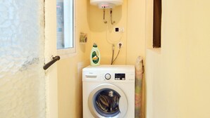Ein kleiner Hauswirtschaftsraum mit Waschmaschine, Warmwasserbereiter und Fenster.