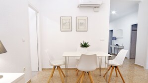 Ein moderner Essbereich mit einem weißen Tisch und Stühlen, einer Zimmerpflanze und zwei gerahmten Bildern an der Wand.