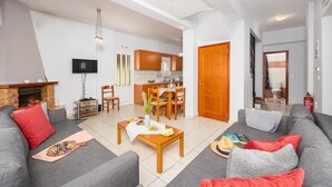 Una sala de estar moderna con chimenea, sofás grises, una mesa de centro de madera y un comedor con sillas de madera.