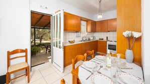 Una cocina moderna con armarios de madera, una mesa de comedor preparada para cuatro personas y vistas al exterior.