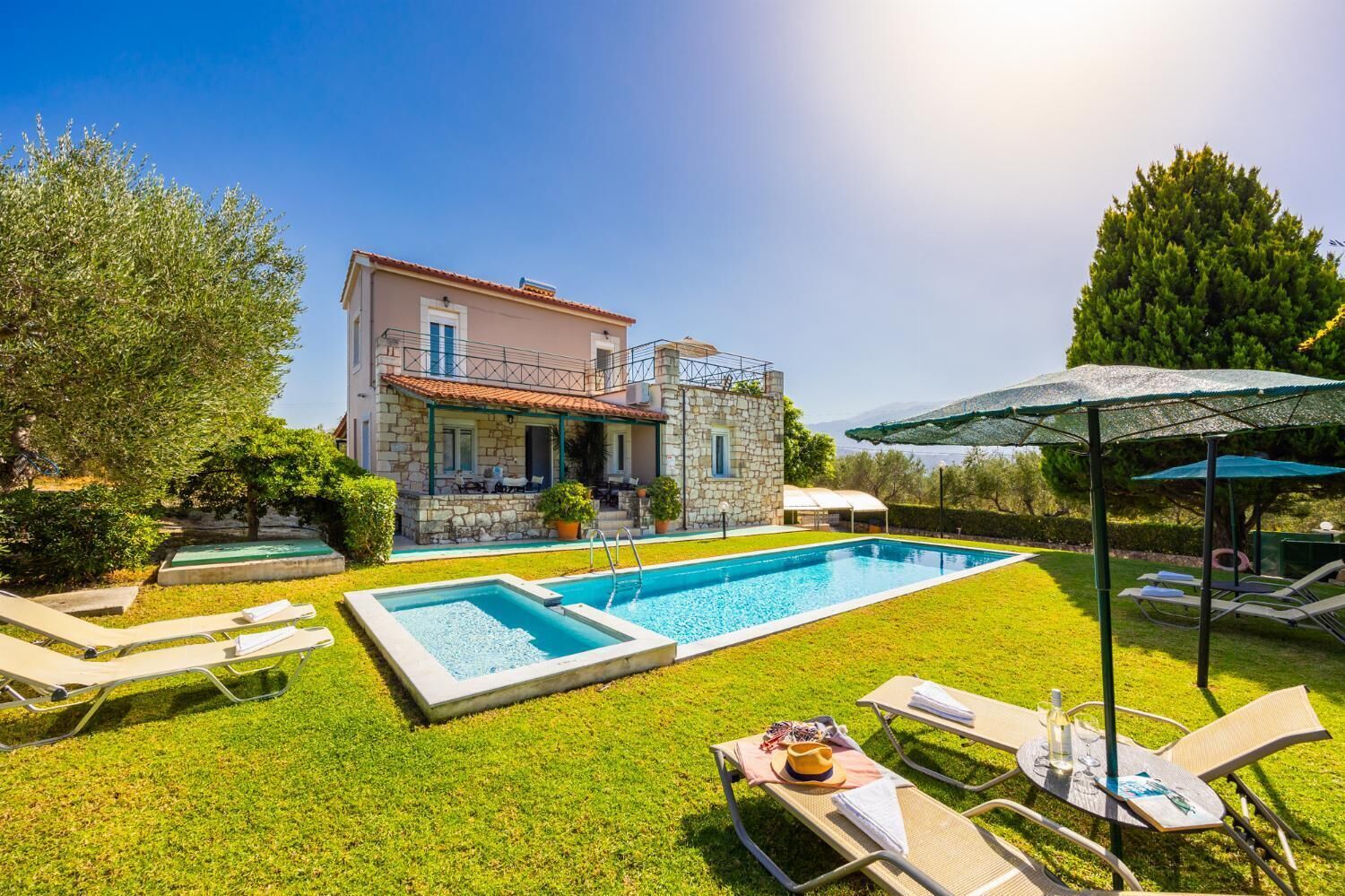 Ein zweistöckiges Steinhaus mit Swimmingpool, Sitzgelegenheit im Freien und einer überdachten Terrasse.