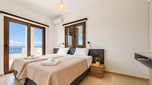 Ein Hotelzimmer mit zwei Betten, einem Balkon, einem kleinen Nachttisch mit Pflanze und einer Klimaanlage.