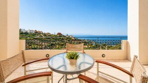 Ein Balkon mit Glastisch, Korbstühlen und einem Blumentopf.