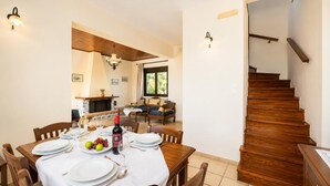 A dining area with a wooden table set for four, a fireplace, and a staircase. - Ekklisies Tria Large Private Pool, A/C, WiFi (Apokoronos)