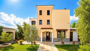 A two-story building with a stone archway entrance, a tiled pathway leading to the door, and a well-maintained garden with potted plants. - Ekklisies Tria Large Private Pool, A/C, WiFi (Apokoronos)
