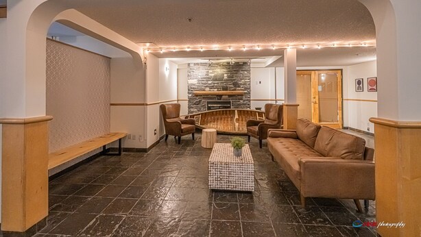 A spacious lounge area with a stone fireplace, leather sofas, and a coffee table.