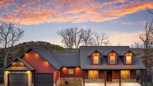 A two-story house with a red exterior, stone foundation, and a large front porch. - Norfork Lake: Family Retreat  (Calico Rock)
