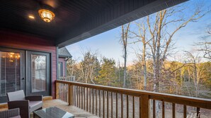 A covered deck with wicker furniture and a view of trees. - Norfork Lake: Family Retreat  (Calico Rock)