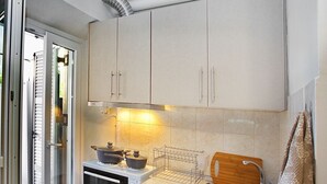 Una cocina compacta con estufa, lavamanos y armarios.