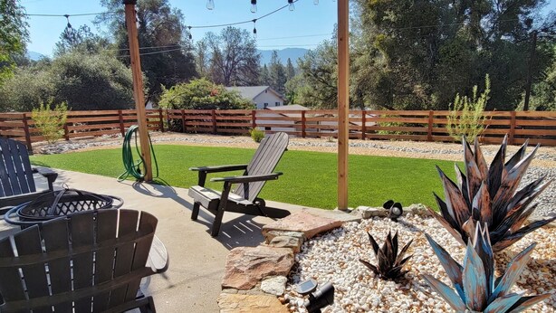 A patio area with outdoor furniture, a stone wall, and decorative plants. - Cozy Home Near Park Entrance, Bass Lake, Restaurants & Shops (Oakhurst)
