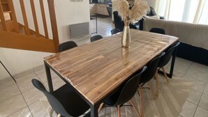 A dining area with a wooden table, black chairs, and a decorative vase. A staircase is visible in the background, leading to another level.