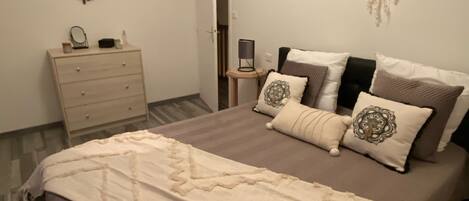 Un dormitorio con cama, cómoda y un espejo adosado a la pared.