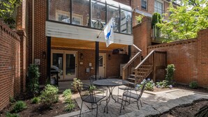 Ein Ziegelgebäude mit überdachter Terrasse, Sitzgelegenheiten im Freien und einer Flagge.