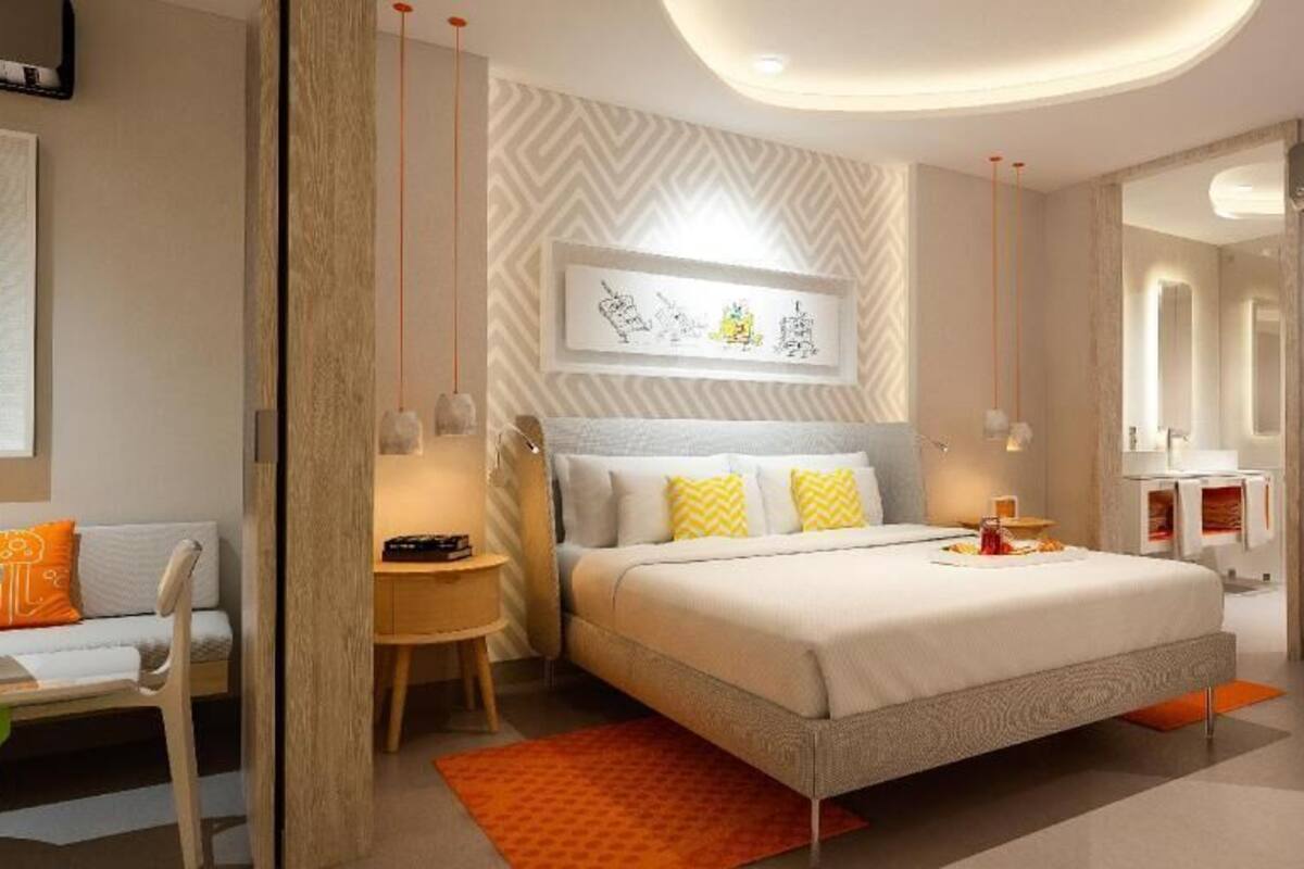Une chambre à coucher moderne avec un lit, des tables de chevet, une chaise et un miroir.