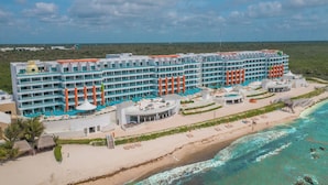 Un hotel grande con varios pisos, ubicación frente al mar y zona de piscina.