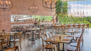 Un restaurante espacioso con paredes de ladrillo, mesas y sillas de madera, y lámparas colgantes.