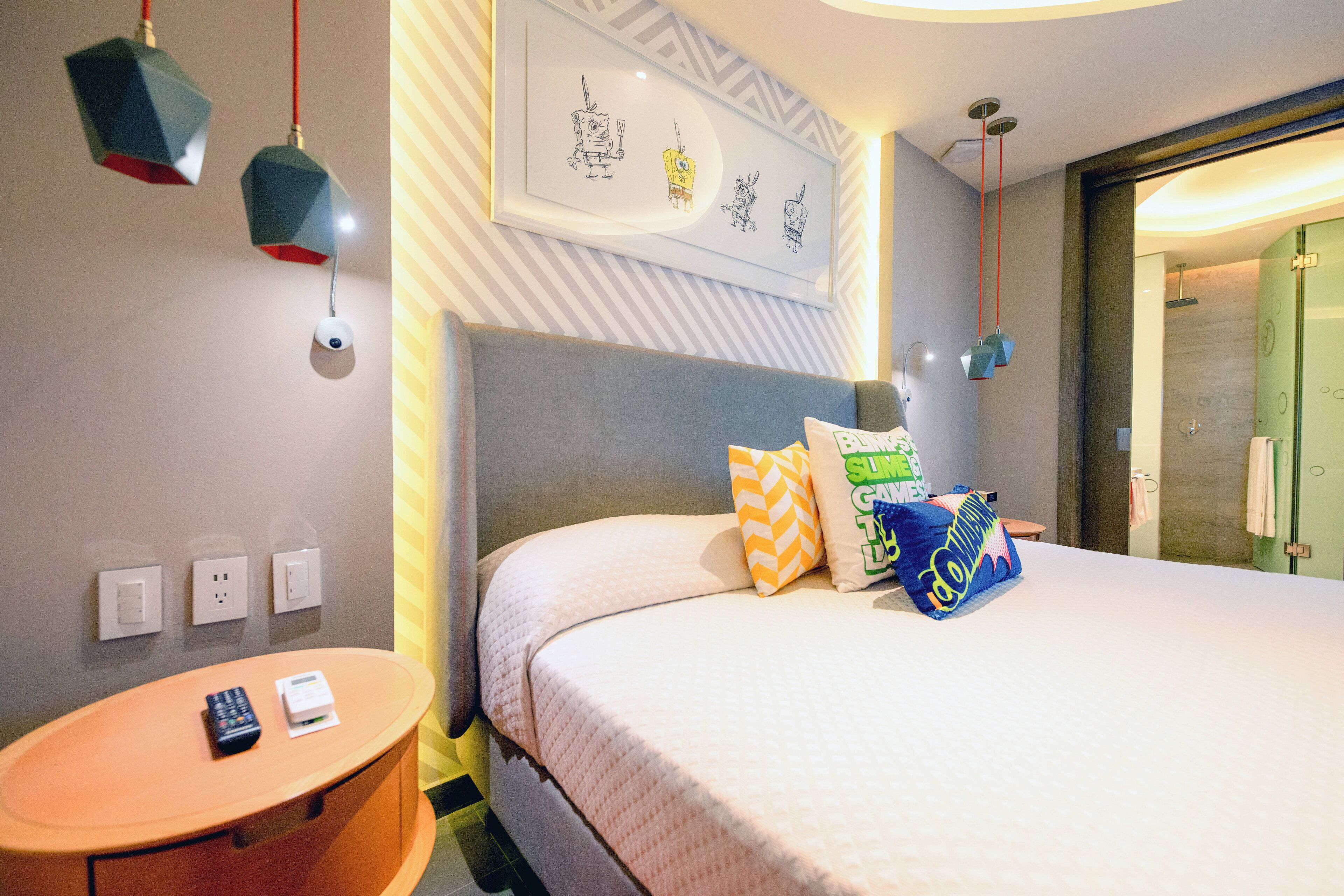 A hotel room with a bed, bedside table, and a wall-mounted artwork.