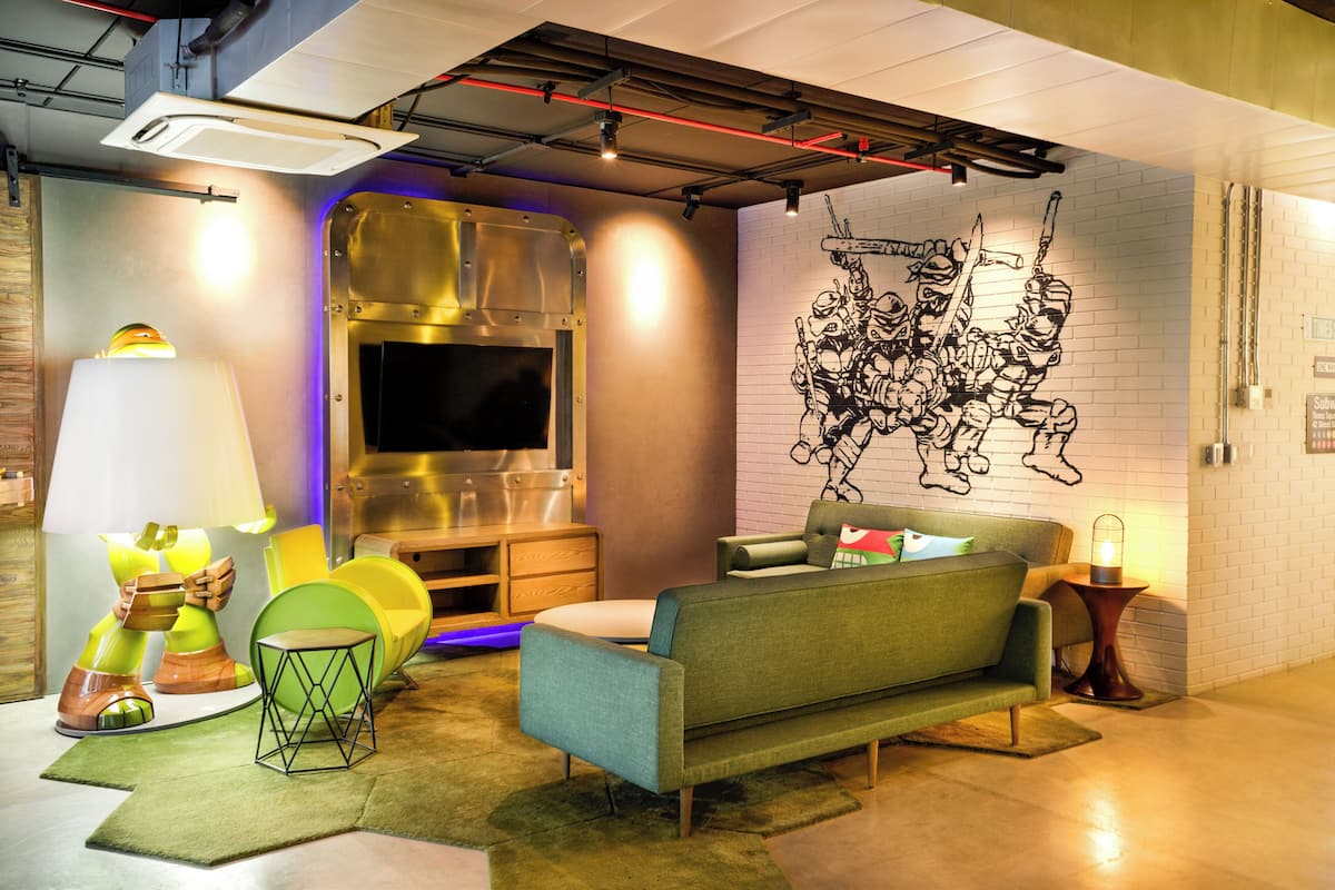 Un salon moderne avec un canapé, un téléviseur et une fresque murale originale.