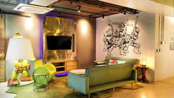 A modern living room with a sofa, a TV, and a unique wall mural.