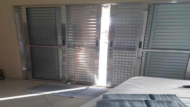 A bedroom with a bed, a wardrobe, and a sliding door. - House Located in the Center of Guape Mg (Guapé)