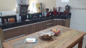 A kitchen with a wooden table, a notebook, a decorative bowl, and a fruit bowl. - House Located in the Center of Guape Mg (Guapé)