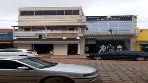 A multi-story building with a storefront labeled "mania store" and a car parked in front. - House Located in the Center of Guape Mg (Guapé)