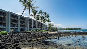 A hotel with multiple floors, a rocky shoreline, and palm trees. - Lovely Oceanfront 2/Bdrm, 4th Floor Condo with A/C at the Kona Bali Kai Resort (Kailua-Kona)
