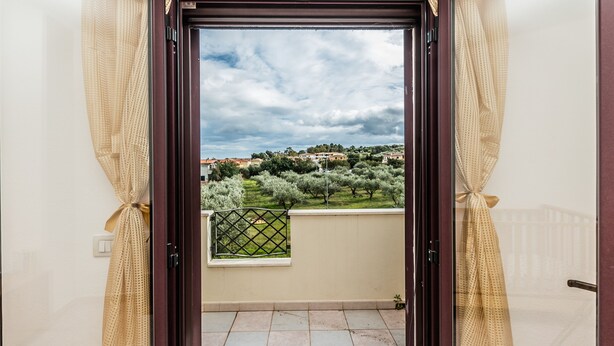 A balcony with a view of a green landscape and buildings in the distance. - Casa Marta (orosei)