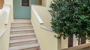 A staircase leading to a building entrance with a small window above it. - Casa Marta (orosei)