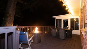 Une terrasse extérieure dotée d’un foyer, d’un espace salon et de guirlandes lumineuses.