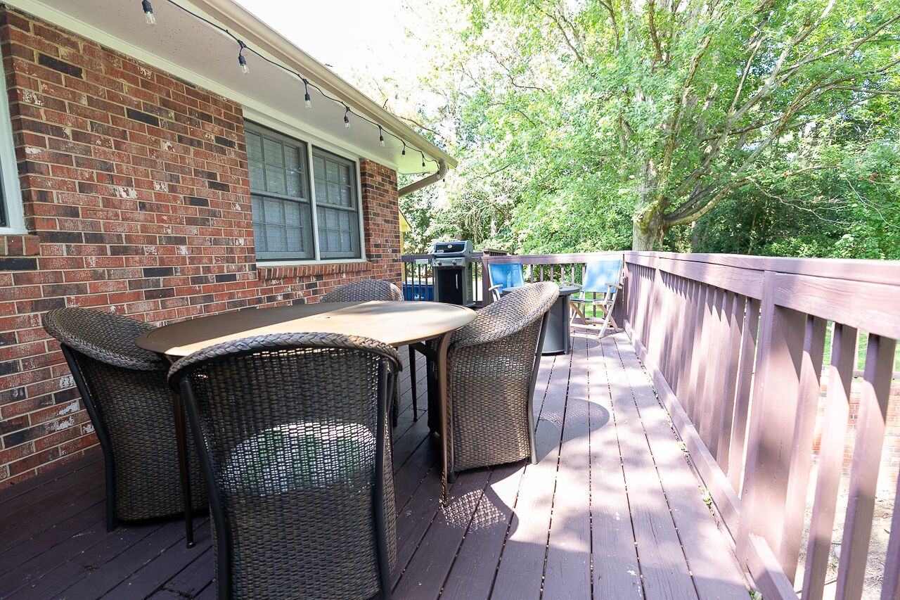 Un patio couvert avec un mur en briques, une table, des chaises et un barbecue.