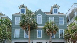 A two-story building with a green facade, multiple windows, and a balcony on the right side. - Summer Dunes Lane 2-  Updated Wild Dunes 5BR Home  with Partial Ocean View! (Isle of Palms)