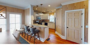 A modern kitchen with a central island, bar stools, and pendant lighting. - Summer Dunes Lane 2-  Updated Wild Dunes 5BR Home  with Partial Ocean View! (Isle of Palms)