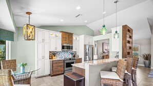 A modern kitchen with white cabinets, stainless steel appliances, and a central island with bar stools. - Marco Island Waterfront Escape | Heated Pool + Hot Tub | Private Dock + Fire Pit (Marco Island)