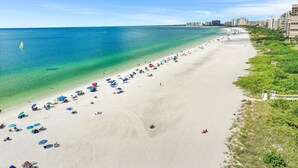 A wide beach with clear turquoise water, umbrellas, and people. - Marco Island Waterfront Escape | Heated Pool + Hot Tub | Private Dock + Fire Pit (Marco Island)