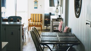 A dining area with a table and chairs, a kitchen in the background, and a beach-themed wall decoration. - Recently Renovated OCEANFRONT CONDO Directly on Beach w/2 bedrooms and 2 baths. (Myrtle Beach)