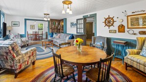 Un salon chaleureux avec une table à manger en bois, des canapés à motifs bleus et blancs et une décoration murale sur le thème de la marine.