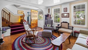 Un salon chaleureux avec un fauteuil à bascule en bois, un fauteuil à motifs à carreaux et un tapis décoré.