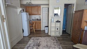 Una cocina amplia con armarios de madera, un refrigerador blanco y un comedor con una silla y una mesa.
