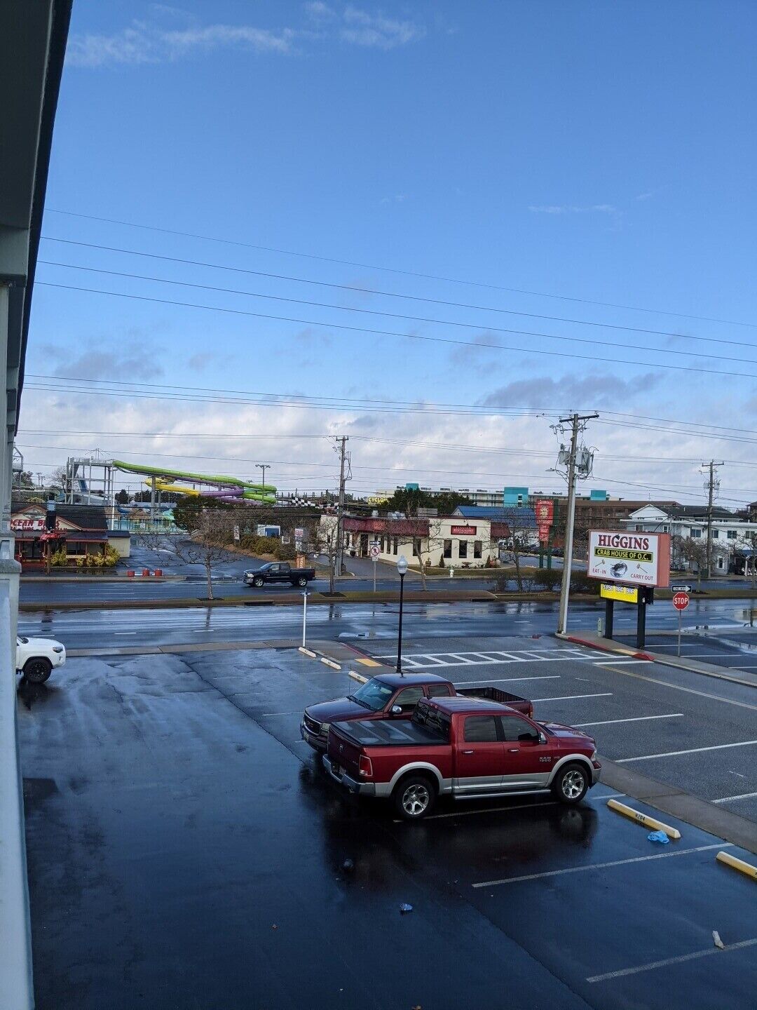 Un parking avec un camion rouge garé au premier plan, un panneau de signalisation indiquant un arrêt obligatoire, et un bâtiment avec une enseigne portant l'inscription « Higgins Crab House of D.C. » à l’arrière-plan.