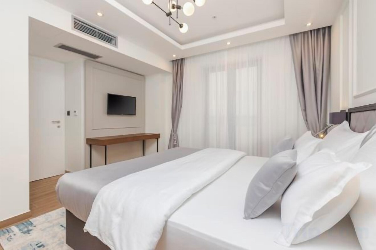 A modern hotel room with a large bed, a flat-screen TV, and a desk.
