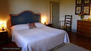 A bedroom with a large bed, two bedside tables with lamps, a wooden chair, a dresser, and a door. - Residence La Pieve Panzano in Chianti with Villa Le Barone pool & tennis access  (Panzano In Chianti)