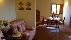 A cozy living room with a striped sofa, a dining table with chairs, and a fireplace. - Residence La Pieve Panzano in Chianti with Villa Le Barone pool & tennis access  (Panzano In Chianti)