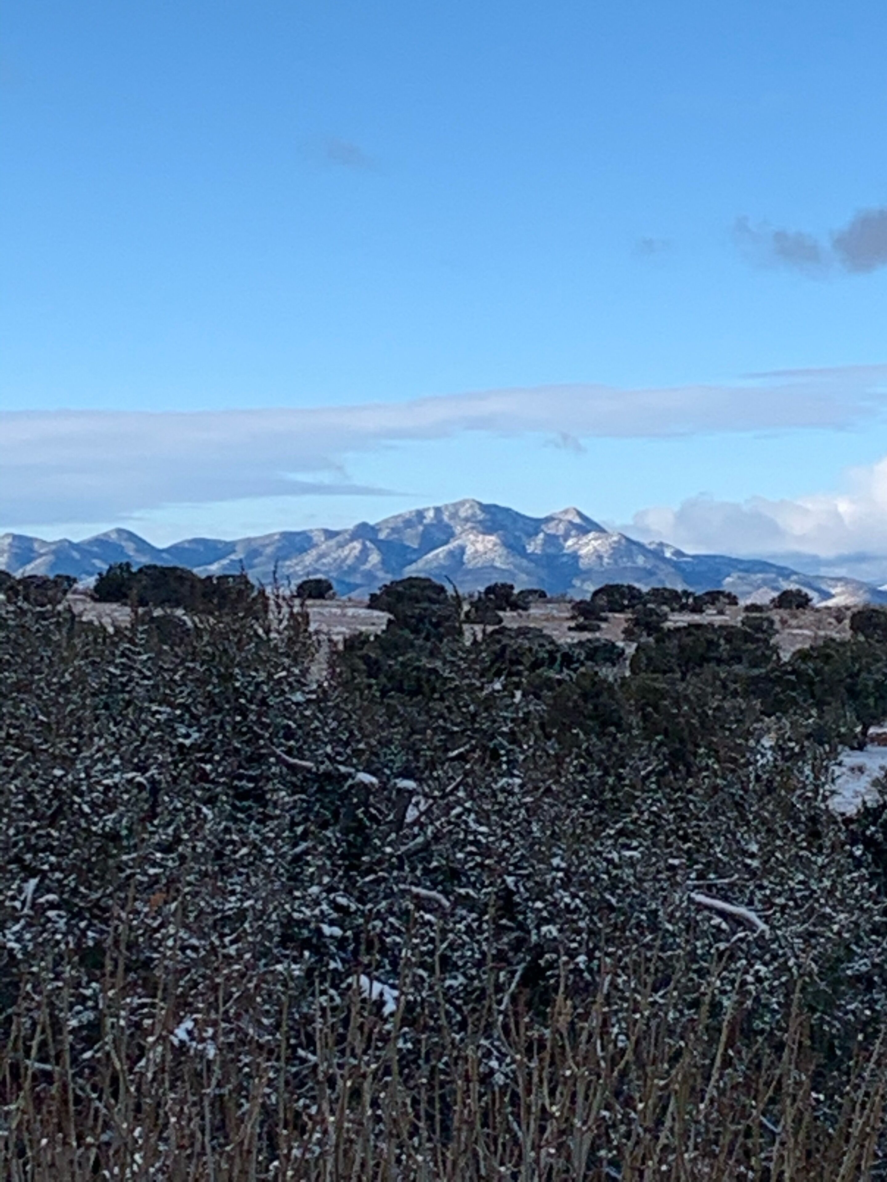 Un paysage montagneux avec des champs enneigés et des sommets lointains.