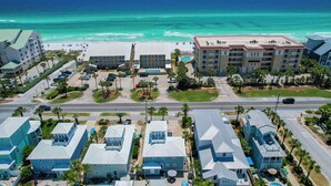 An aerial view of a coastal hotel with multiple buildings, a parking lot, and a beach in the background. - Across Beach, Pool, Pool Table,Ping Pong, Golf Cart Rental, Amazing Yard, 7 BR (Destin)