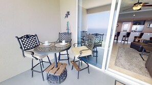 Un coin repas avec une table ronde et des chaises, une cuisine en arrière-plan et une vue à travers une porte vitrée.