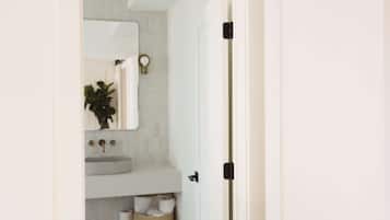 Un bagno con un lavandino bianco, uno specchio e un water.