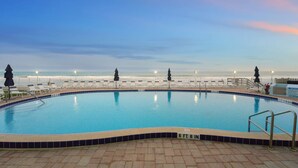 A swimming pool with a view of the beach and ocean at sunset. - Seaside Escape – Ground-Floor Condo with Panoramic Ocean Views, Steps to Beach & Pool 🏝️ (Satellite Beach)